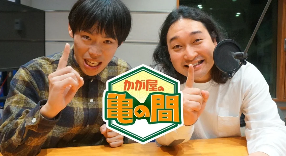 かが屋の二人がスタジオで指をさしながら笑顔でポーズをとっている画像